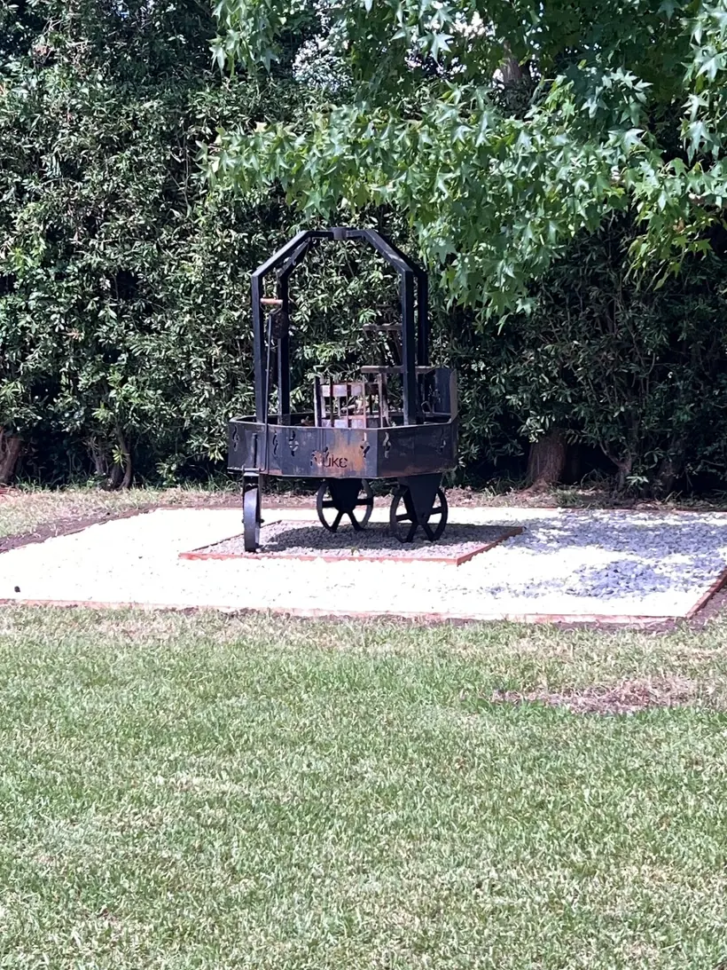 Parrilla antigua tipo carro sobre un sector de piedra con borde de ladrillo